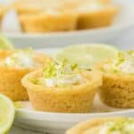 A plate of key lime cookie cups with lime slices.