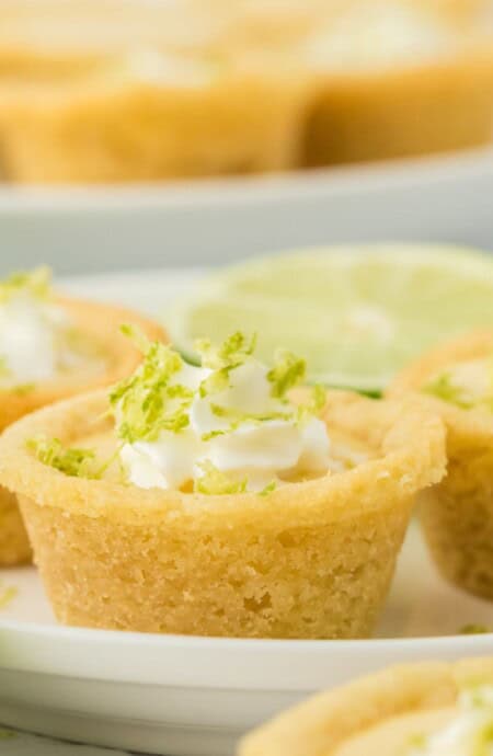 A plate of key lime cookie cups with lime slices.
