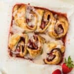 Lazy Strawberry Cinnamon Rolls in a baking pan ready to eat with a bowl of strawberries on the side.