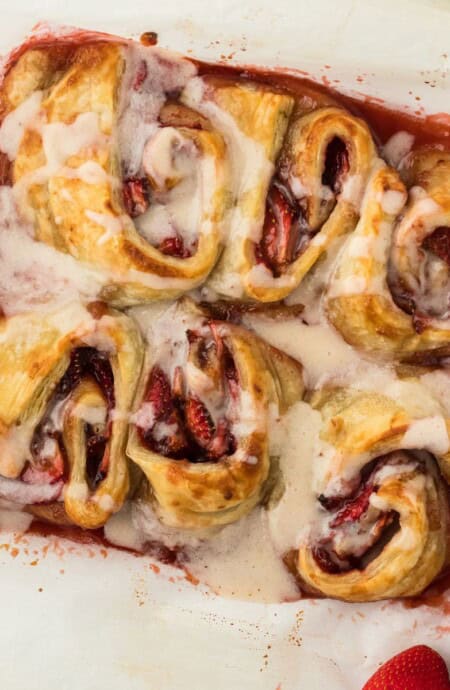 Lazy Strawberry Cinnamon Rolls in a baking pan ready to eat with a bowl of strawberries on the side.