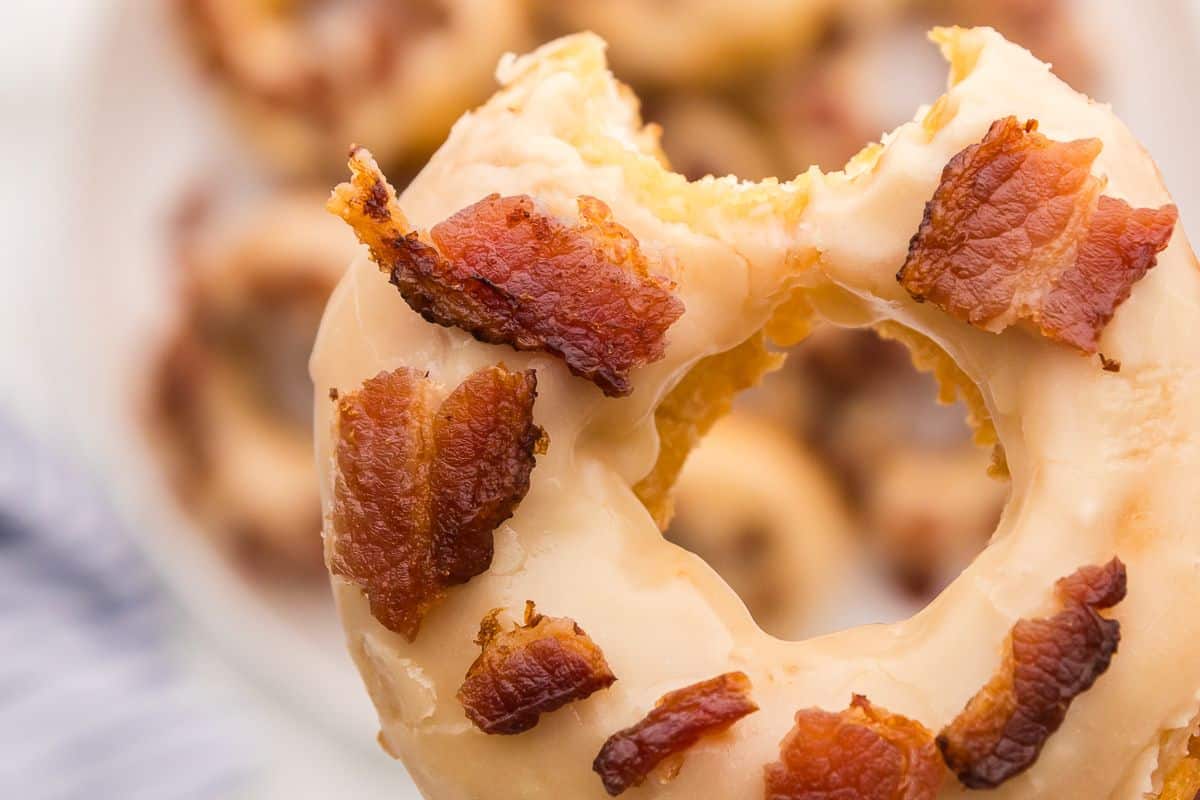 A maple bacon donut with a bite missing.