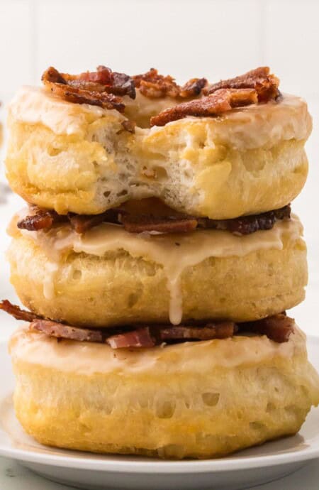 A stack of three maple bacon doughnuts on a plate.