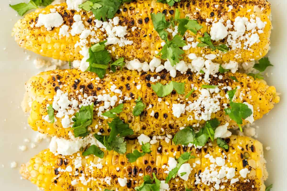 Mexican corn on a platter with goat cheese and cilantro sprinkled over the top.