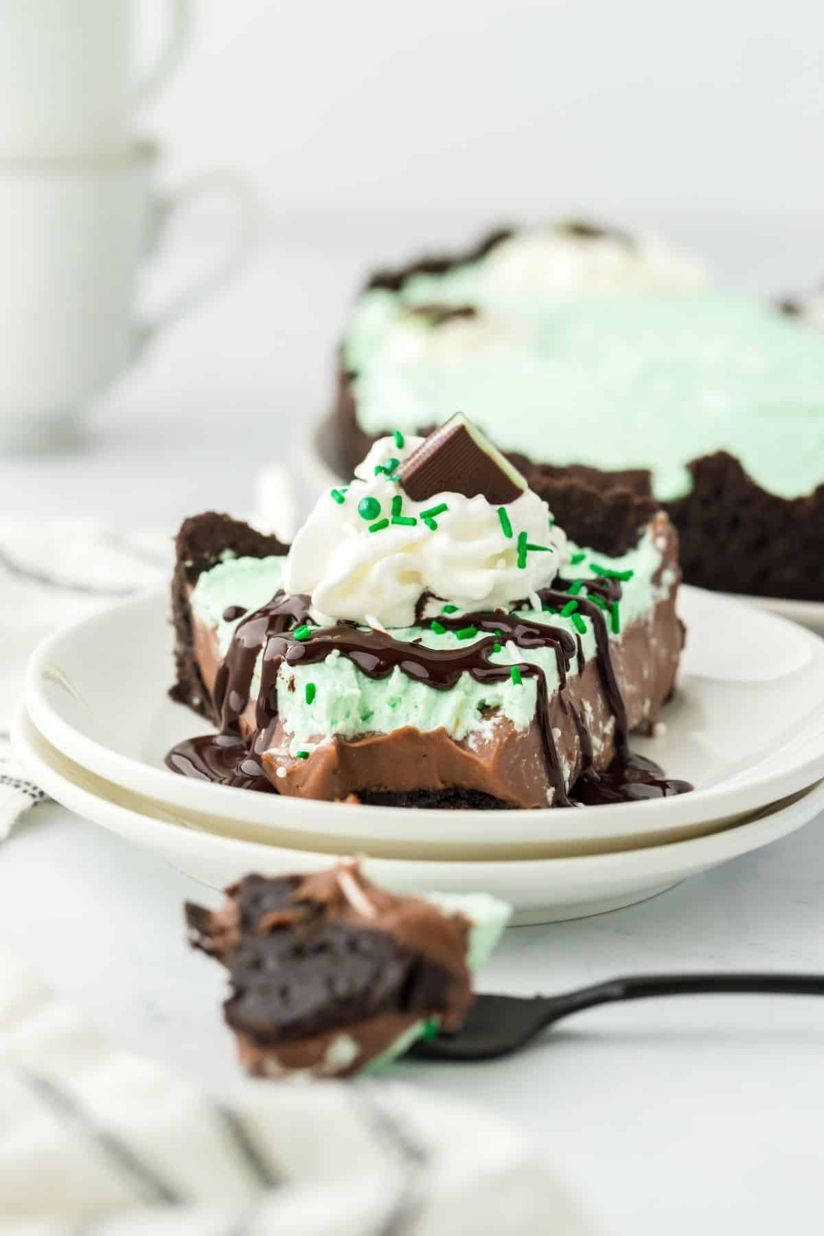 Baileys mint chocolate cream pie on a plate with a fork in front with a bite on it.