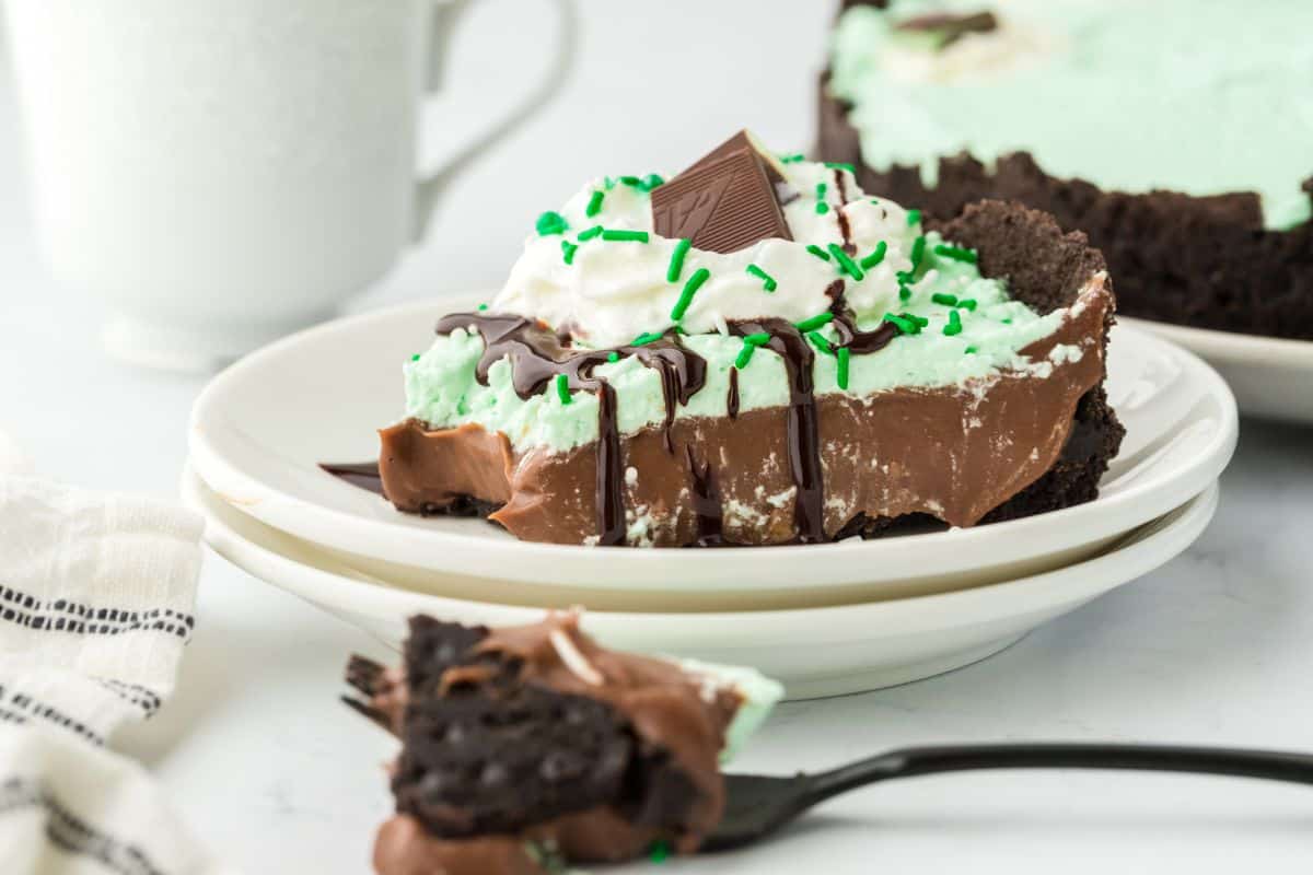 Baileys mint chocolate cream pie slice served on a plate with a bite missing and on a fork on the table in front. 