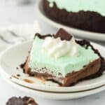 Baileys mint chocolate cream pie on a plate with a few bites missing.