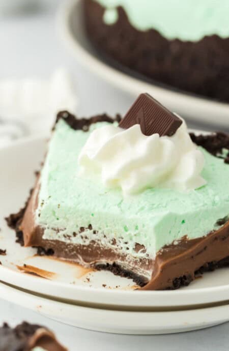 Baileys mint chocolate cream pie on a plate with a few bites missing.