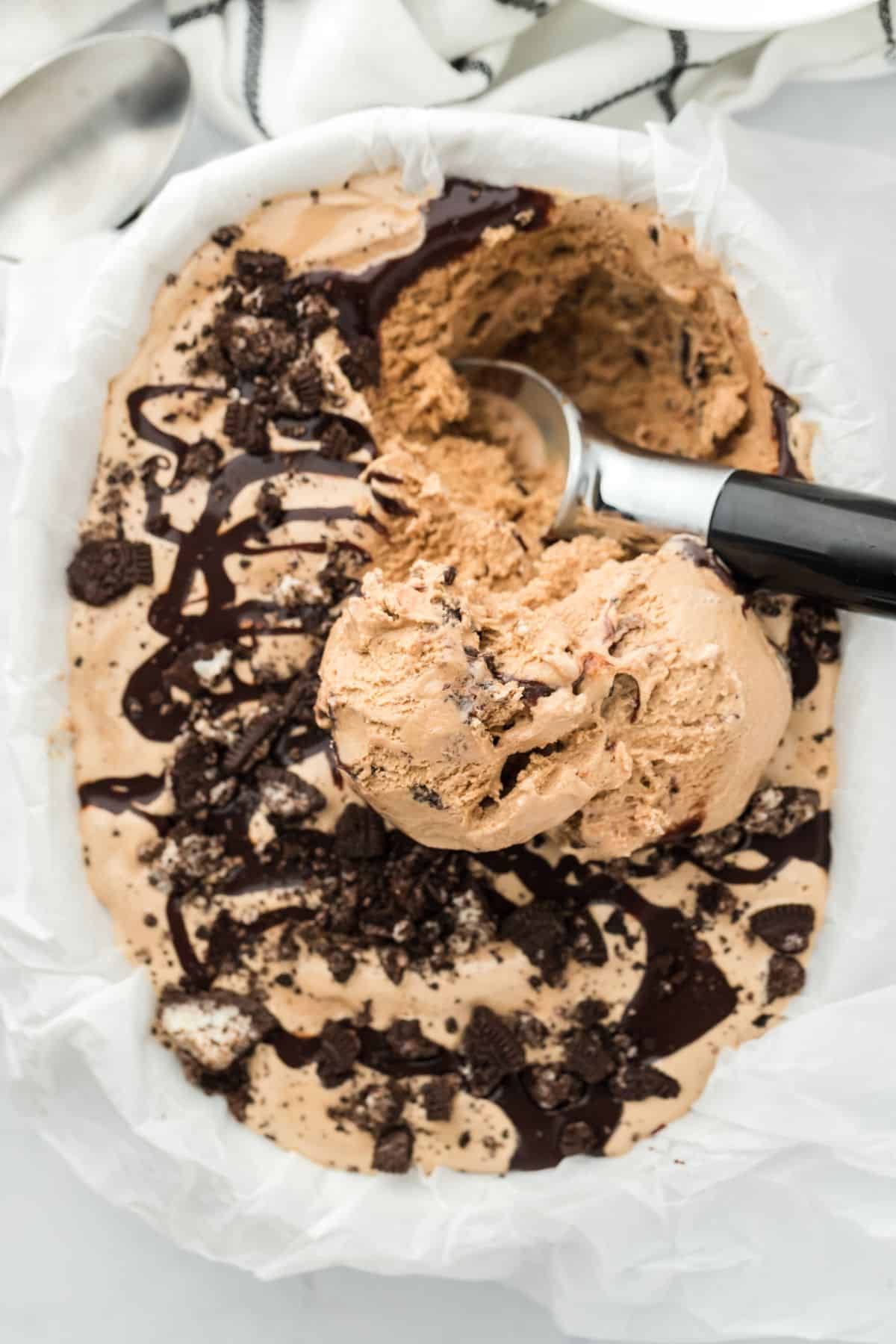 Close up of a tray full of mocha fudge swirl ice cream with a ice cream scoop in it