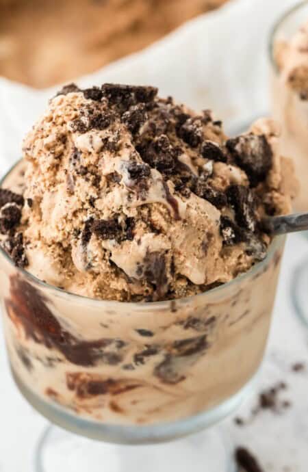 A glass cup full of mocha fudge ice cream with a spoon dipping in.
