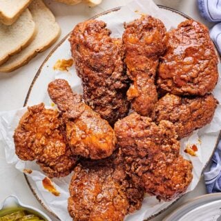 Nashville Hot Chicken Recipe on a white platter with pickles and bread in the background