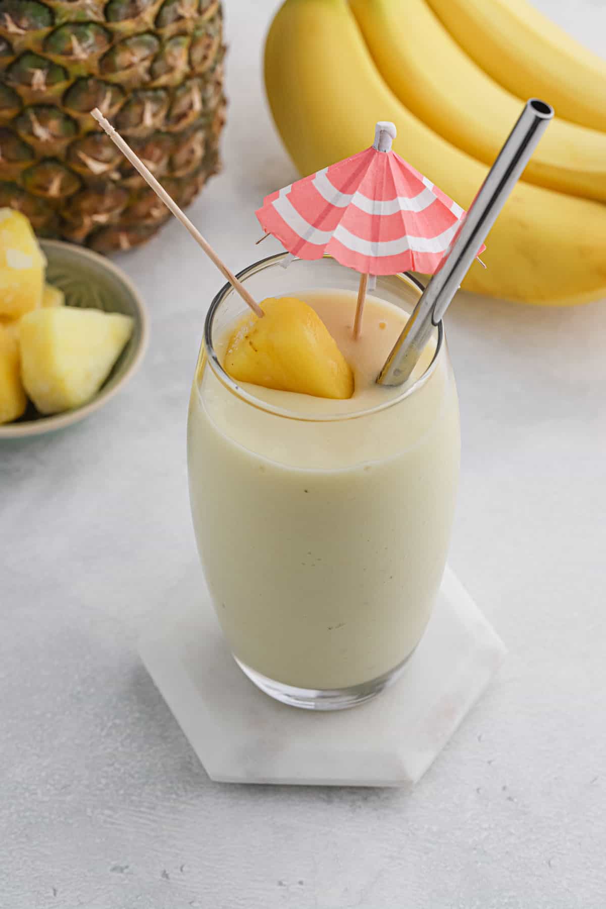 A pina colada smoothie on the table with a lemon wedge and drink umbrella for garnish.