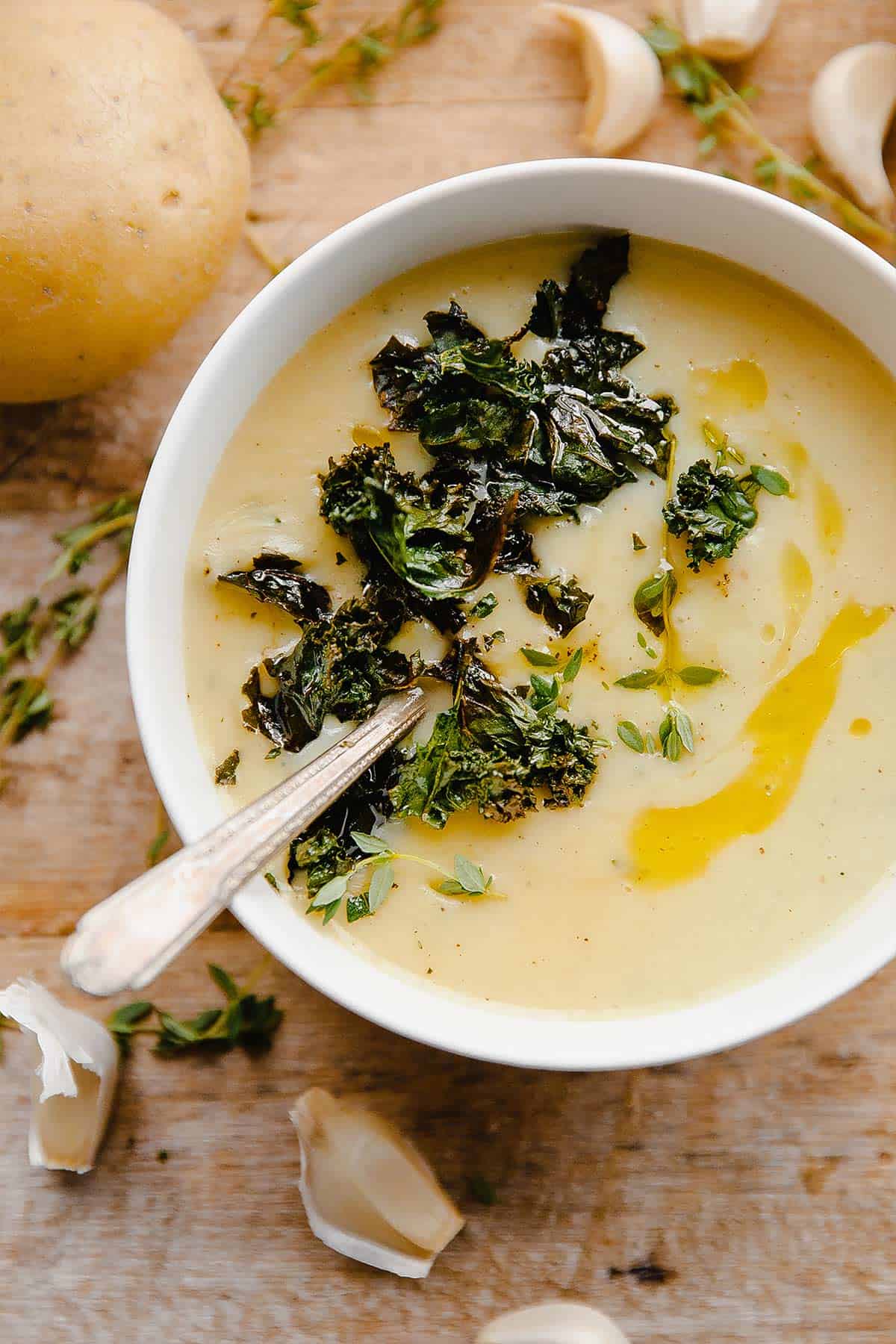 A bowl of potato kale soup topped with crispy kale, thyme and porcini oil.