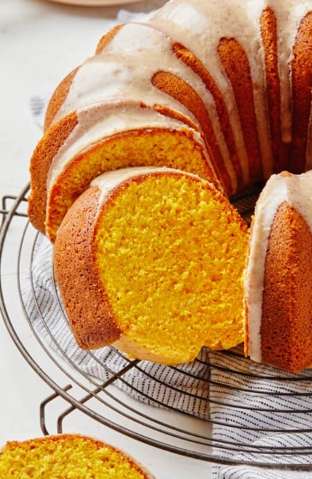 A pumpkin pound cake on a wire rack cut into slices.