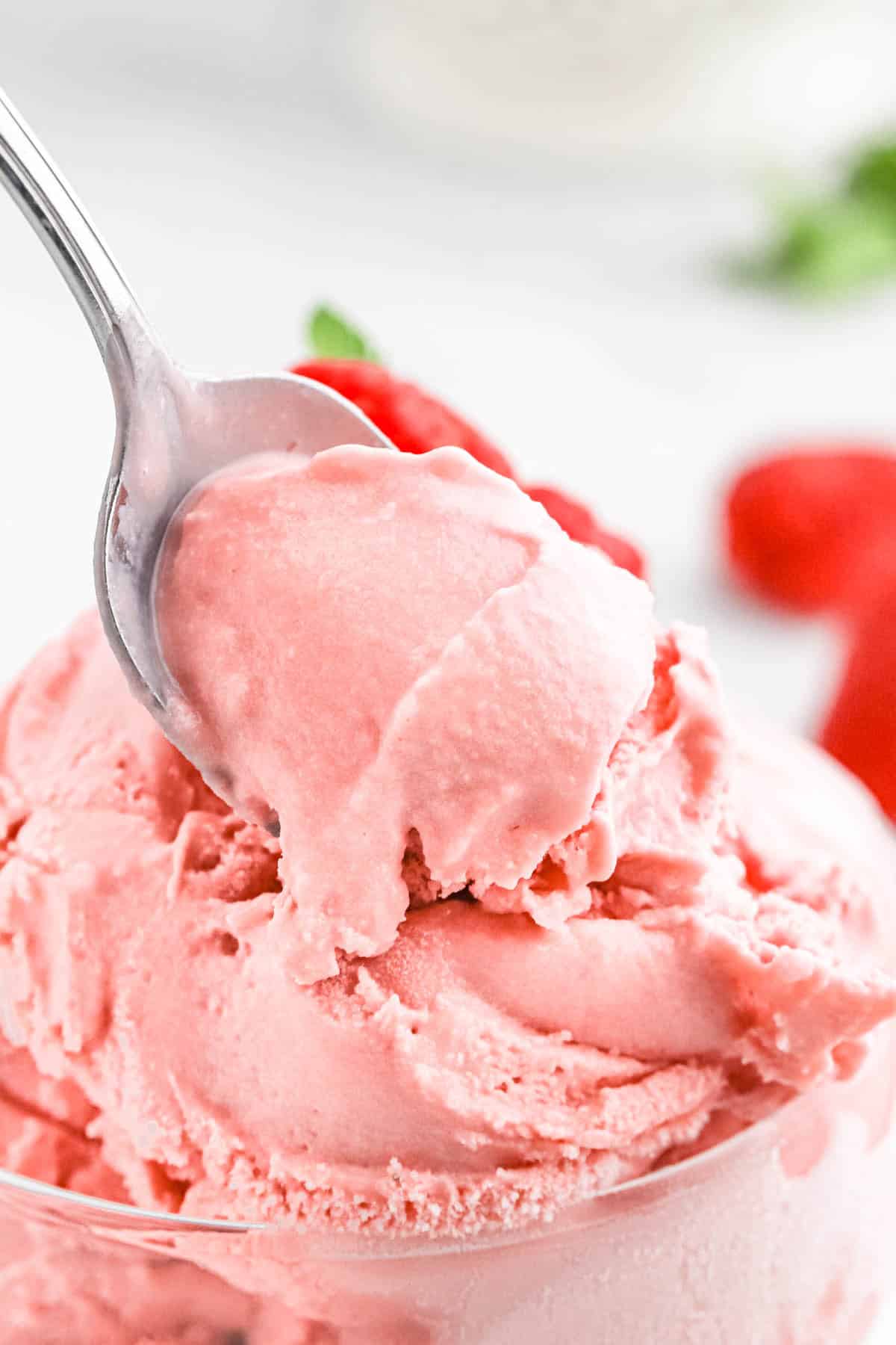 Close up of fresh raspberry ice cream on a spoon up over a bowl.