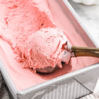 An ice cream scooper in raspberry ice cream
