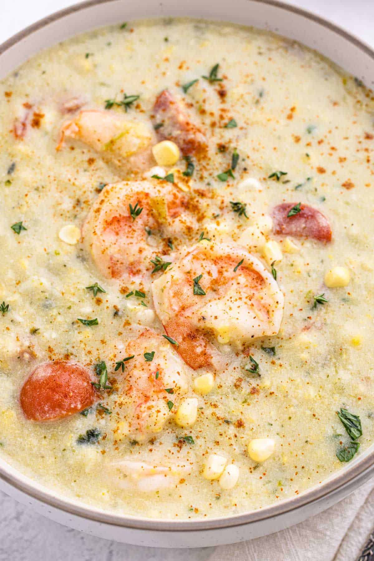 A close up of corn chowder with shrimp shot overhead to focus on the shrimp on top.
