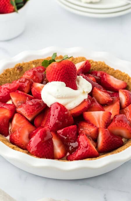 A strawberry custard pie in a white pie dish on the table.