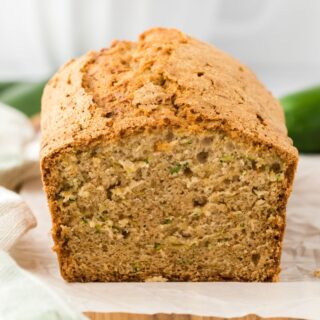 Zucchini bread cake loaf on the table with slice missing to show the inside of the bread.