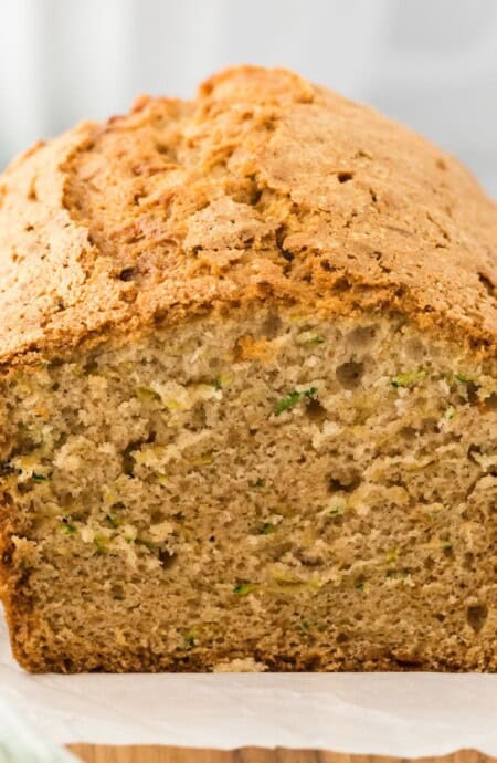 Zucchini bread cake loaf on the table with slice missing to show the inside of the bread.