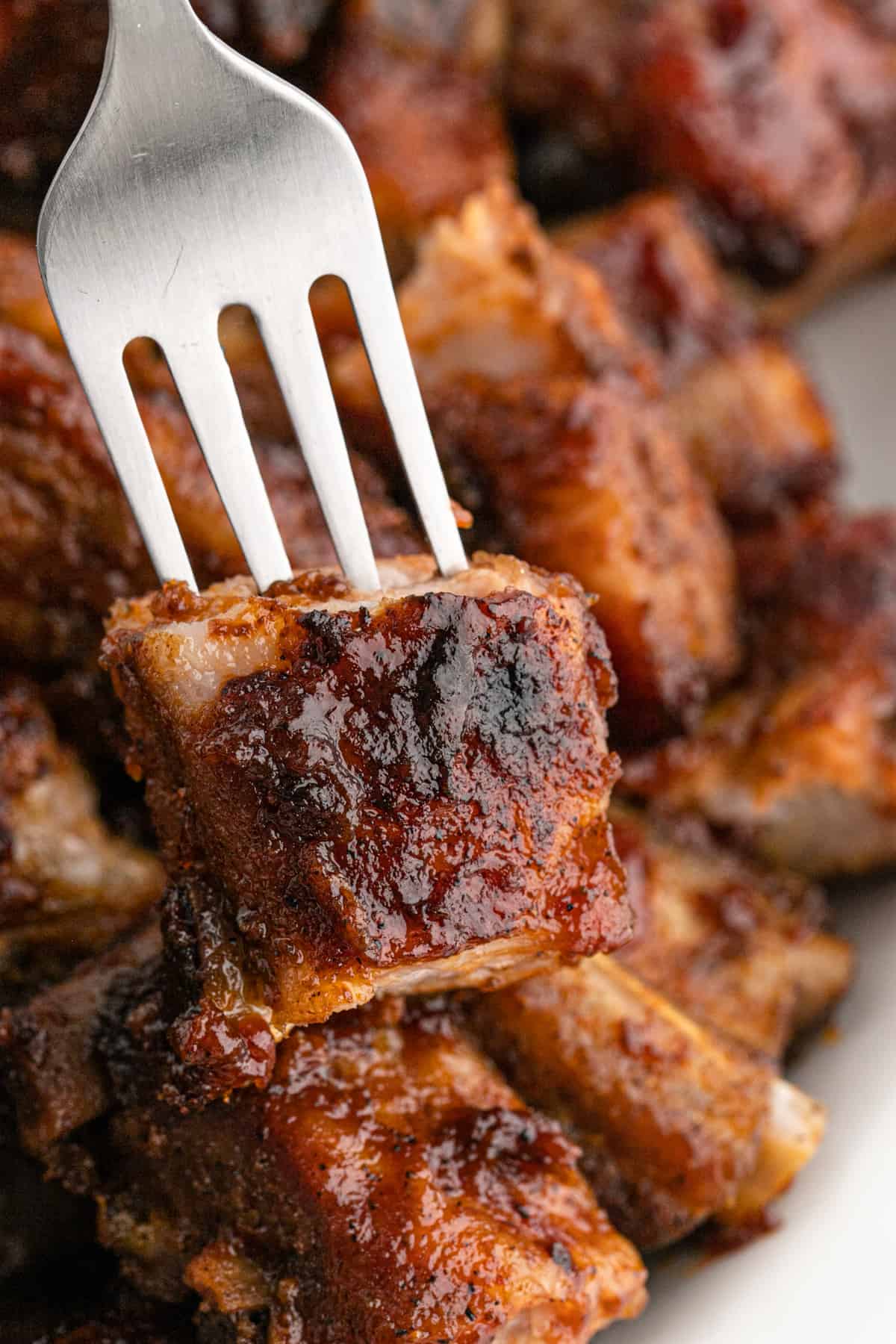 A fork in a rib tip with several pork rib tips in the background ready to enjoy