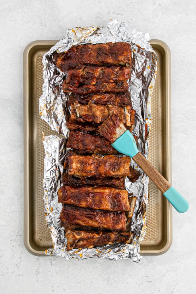 BBQ sauce being basted on baked ribs