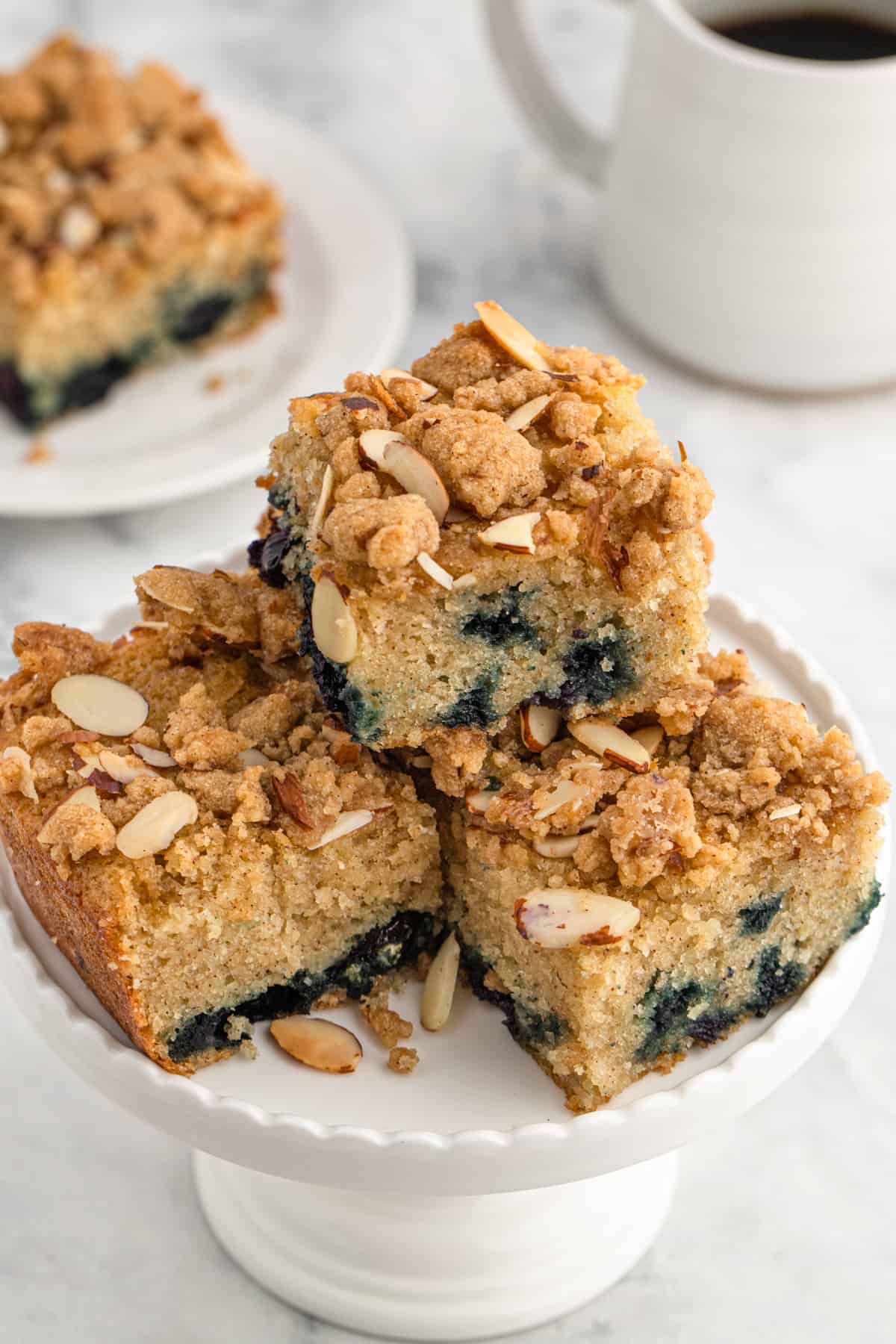 A stack of blueberry crunch cake slices on a white plate