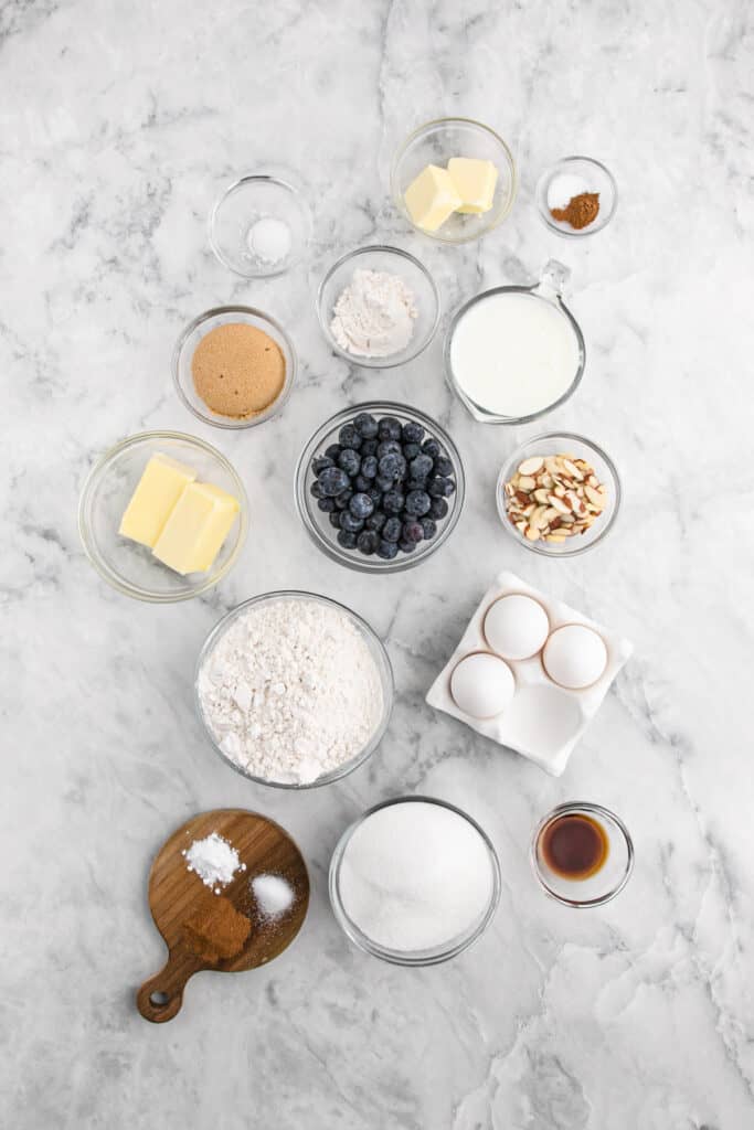 Ingredients to bake a cake in clear bowls on white surface