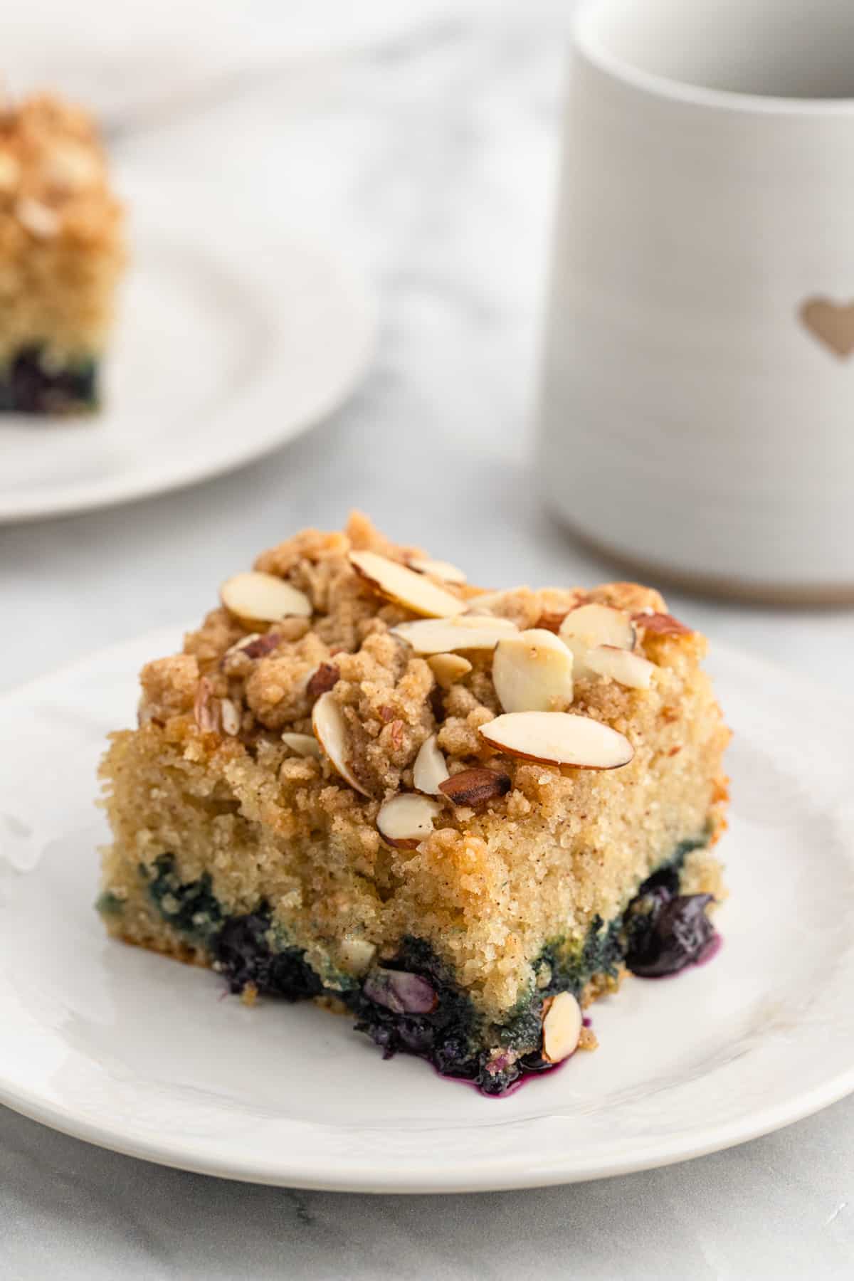 A slice of blueberry crunch cake on. white plate