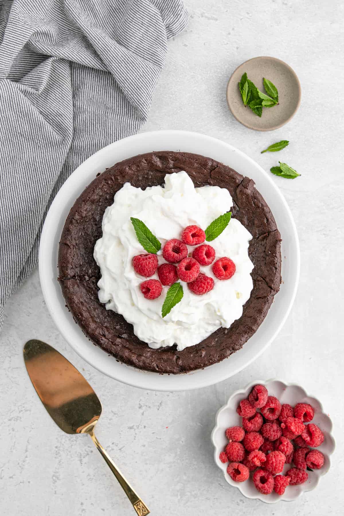 Flourless chocolate cake with whipped cream and raspberries on top ready to serve