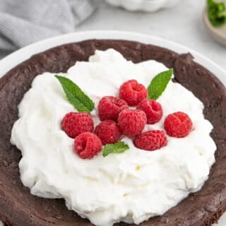 A close up of flourless chocolate cake with berries and whipped cream