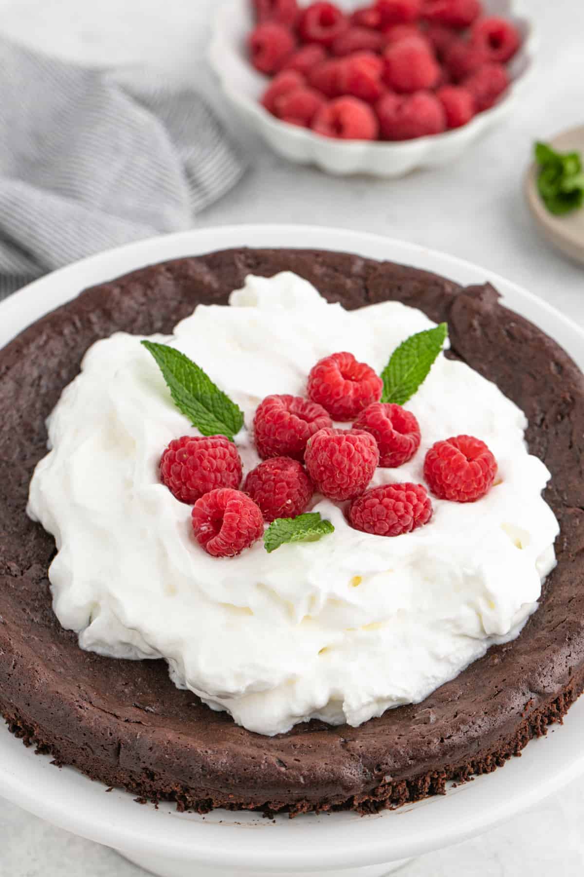 A close up of flourless chocolate cake with berries and whipped cream