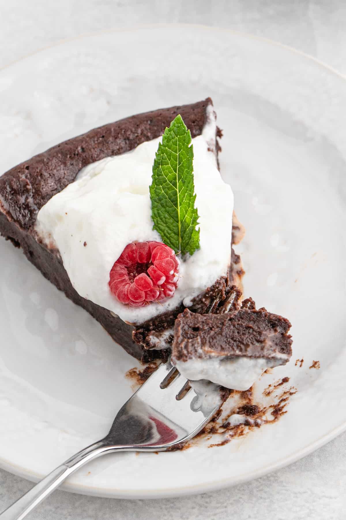 A close up of a slice of chocolate cake being eaten with a fork