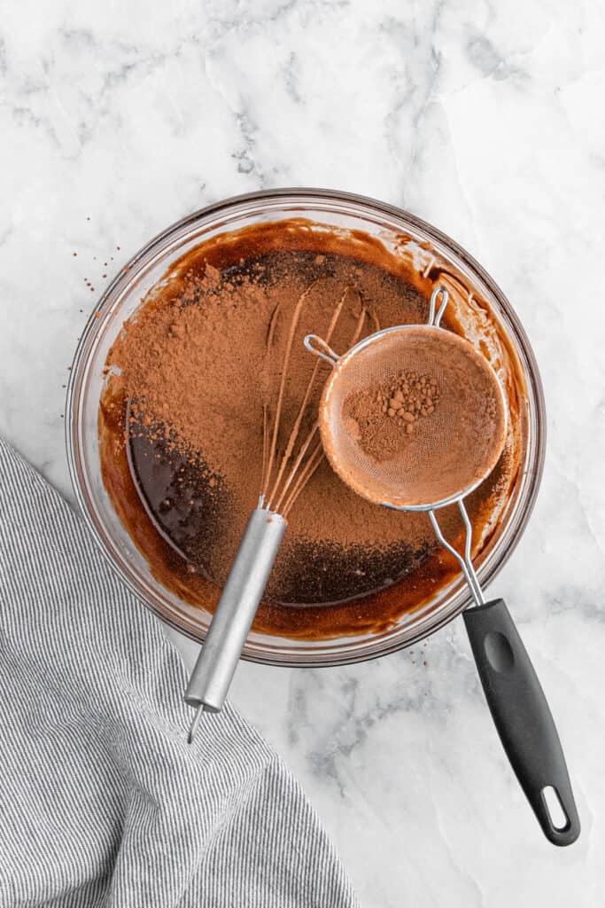 Chocolate cocoa being sieved over chocolate cake batter