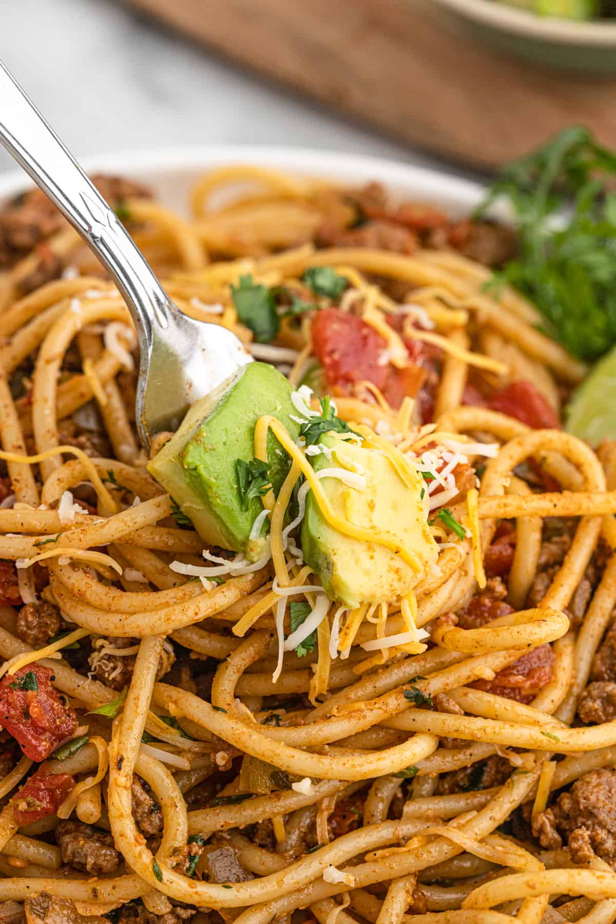 Completed dish of taco spaghetti garnished with lime wedges.