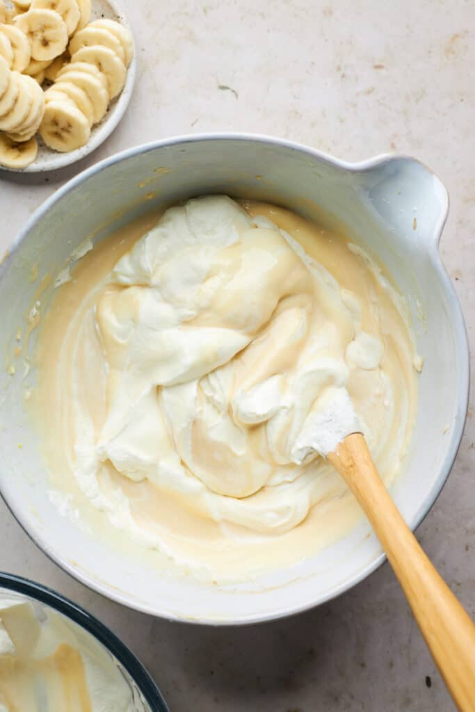 Condensed milk and vanilla being poured into an ice cream mixture and being folded