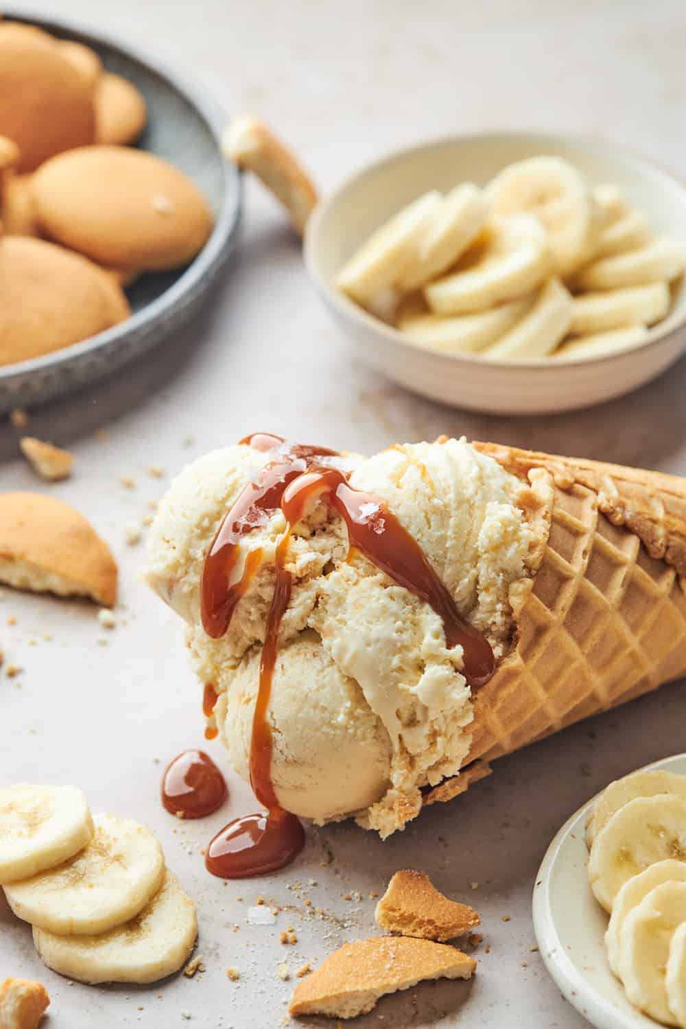 Caramel sauce drizzled over banana pudding ice cream in a waffle cone
