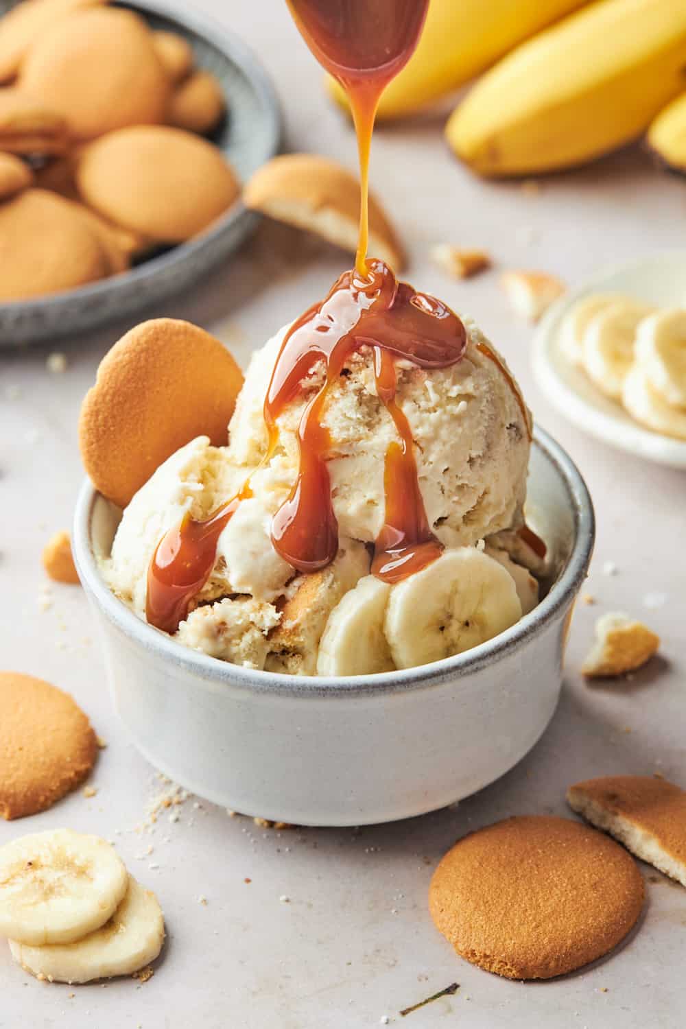 Banana pudding ice cream scoops in a bowl with caramel sauce poured on top