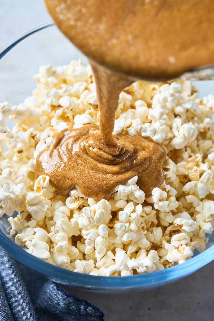 Pouring caramel overtop of popcorn.