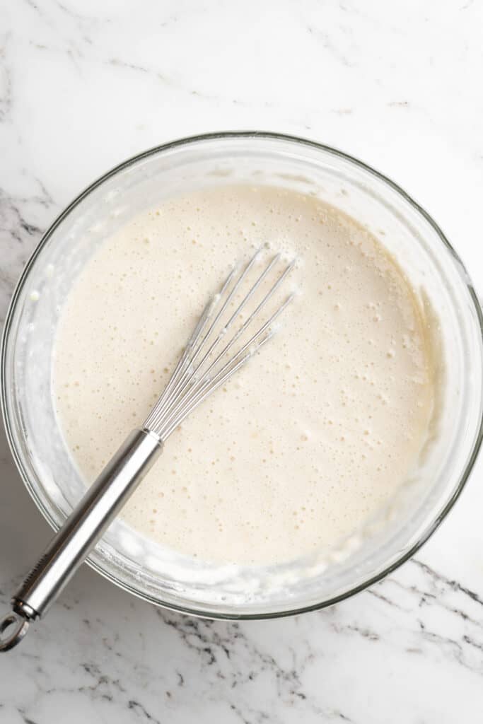 A dough batter whisked together in a clear bowl