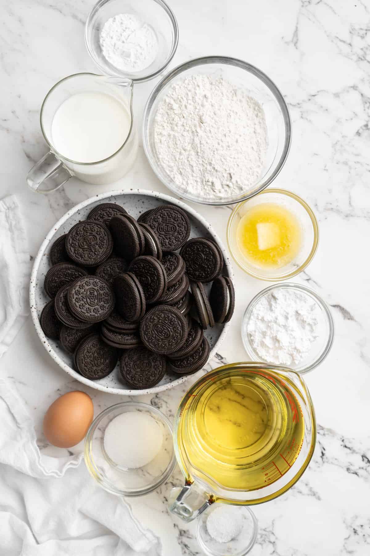 Oreos in a clear bowl with dough ingredients around it