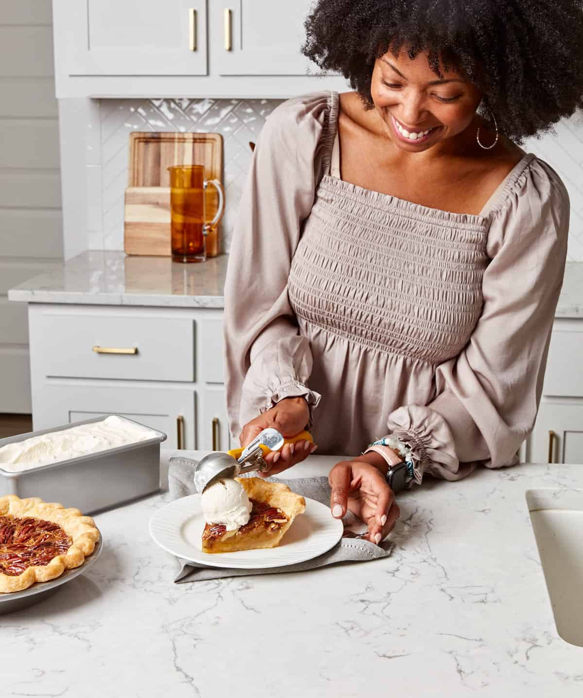 Black woman adding a scoop of ice cream to a slice of pecan pie.
