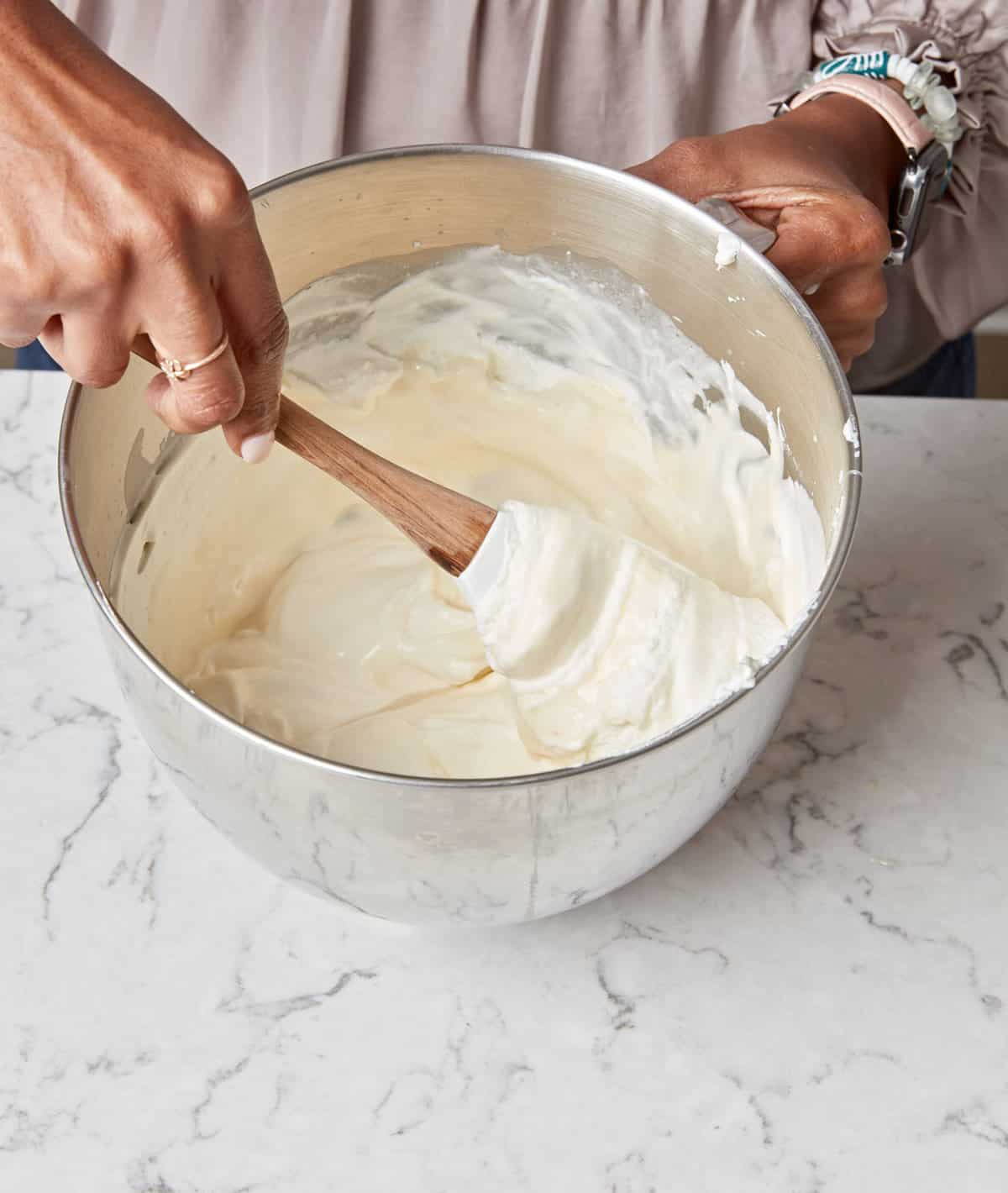 Woman folding whipped cream into vanilla ice cream base.