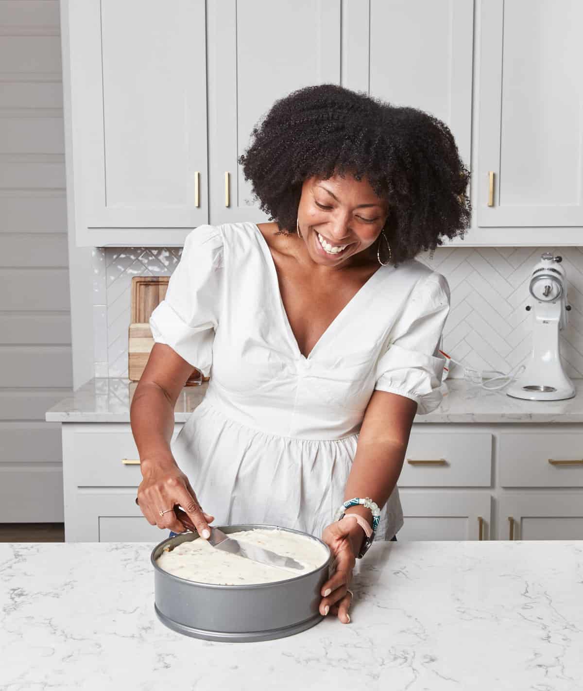 A Black woman spreading ice cream into a springform pan.