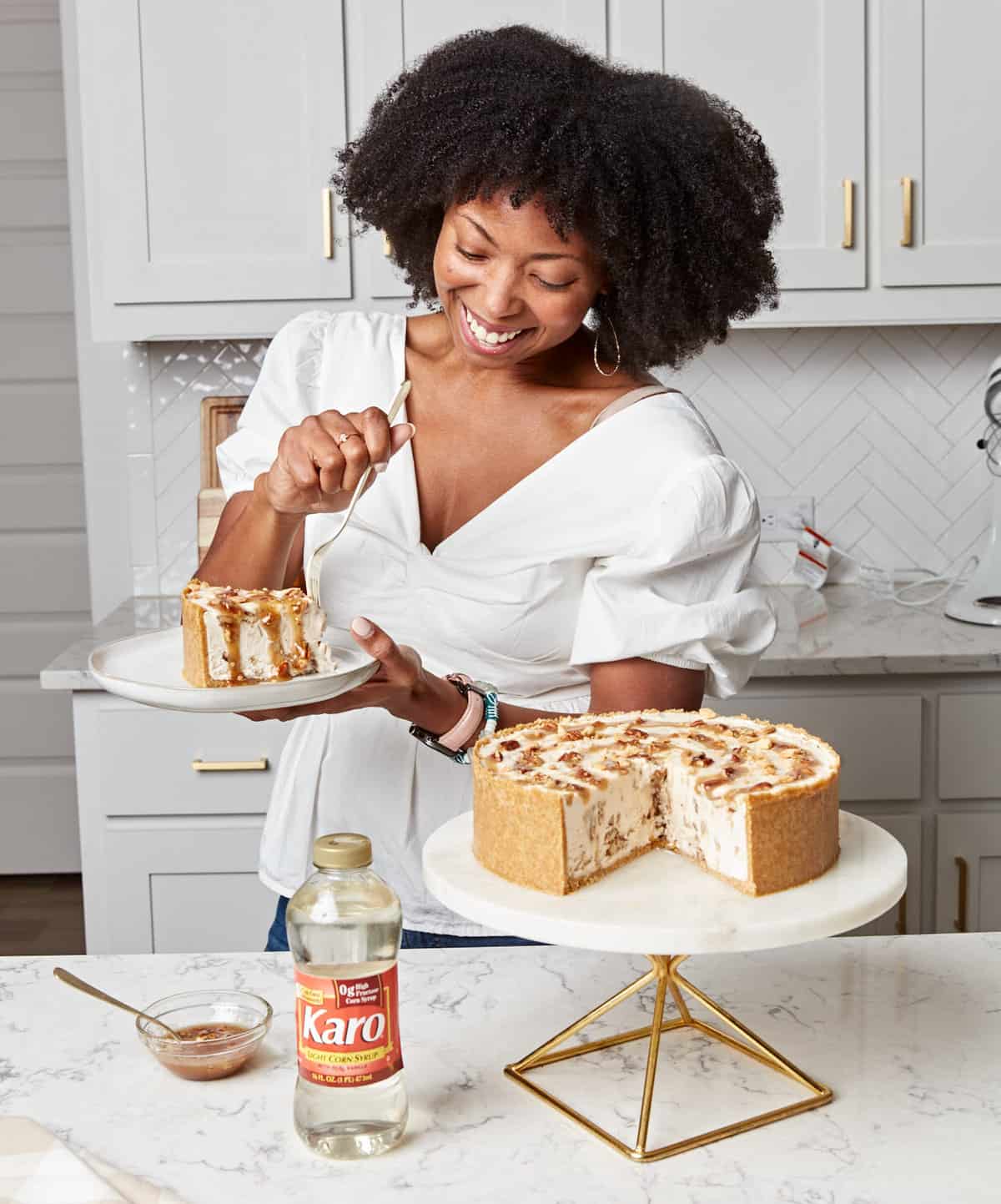 A Black woman holding a plate with a slice of pecan pie ice cream cake.