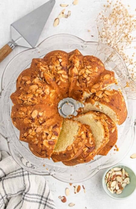 Almond pound cake on a cake stand with a few slices cut.