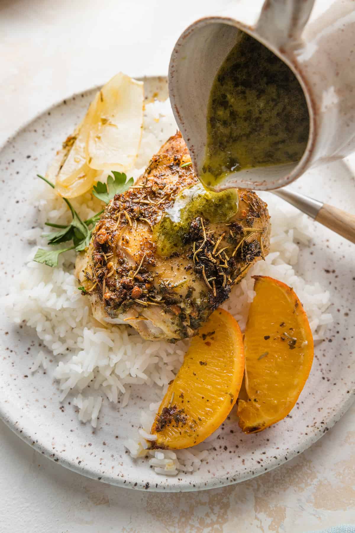 Orange Herbed Chicken over rice on a dinner plate.
