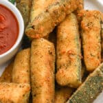 Air fried zucchini plated with dipping sauce.