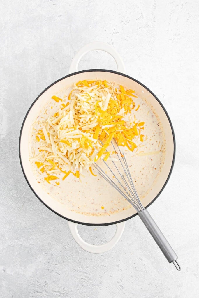 Shredded cheeses in pot of milk and heavy cream