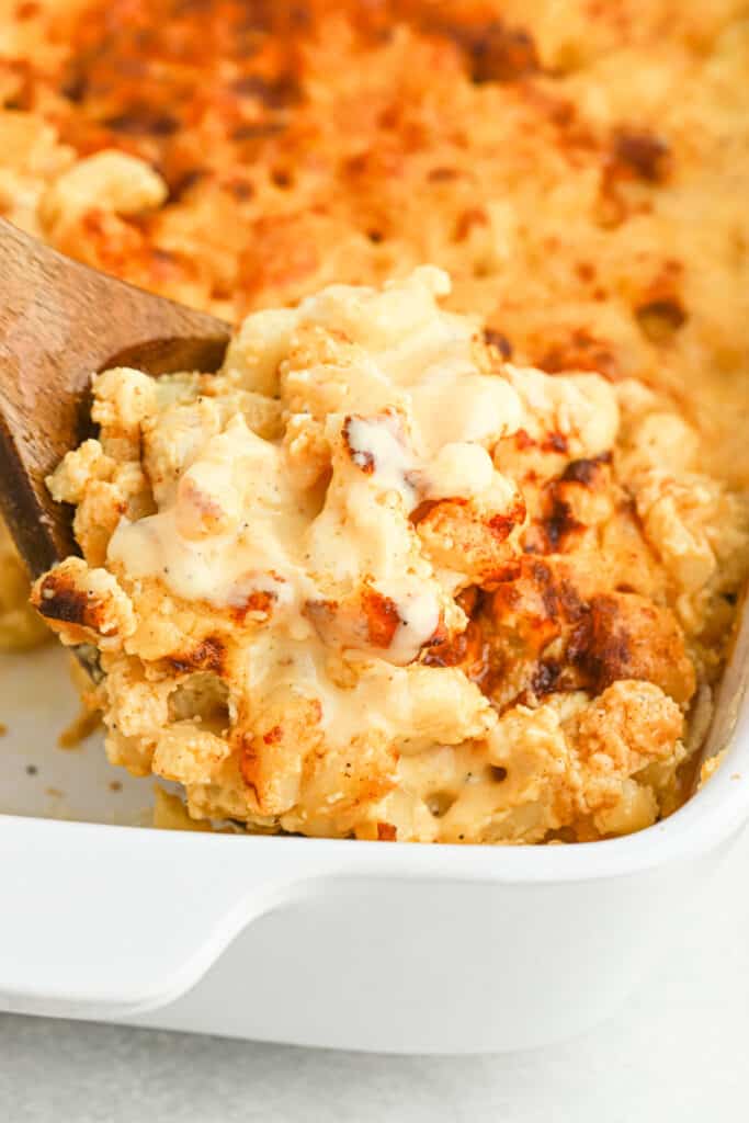 Baked Macaroni and Cheese on a spoon being lifted out of a baking pan