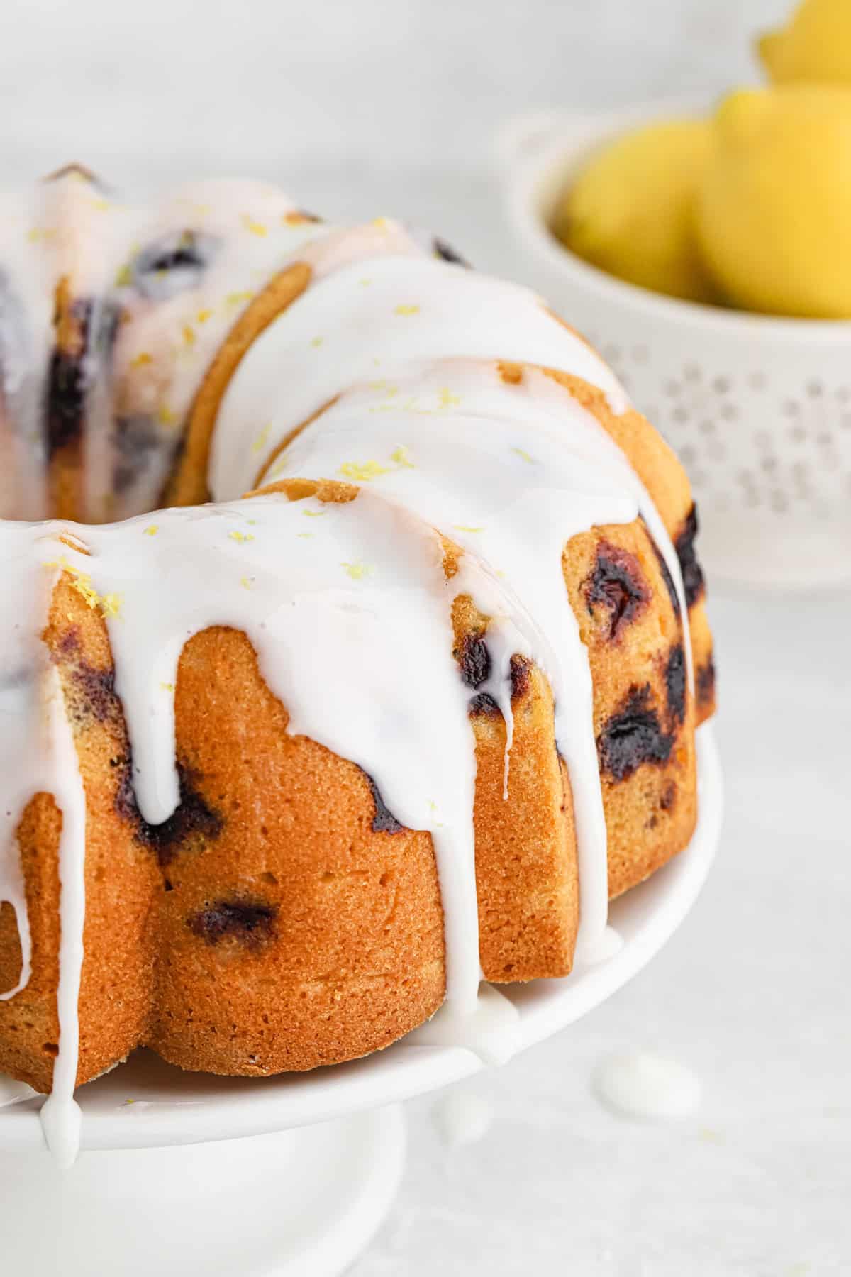 Closeup of lemon blueberry pound cake with thick glaze dripping down the sides